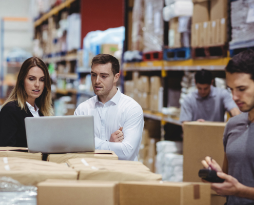 Workers In Warehouse Looking At Data On Computer